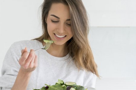 Une femme mange une salade de légumes