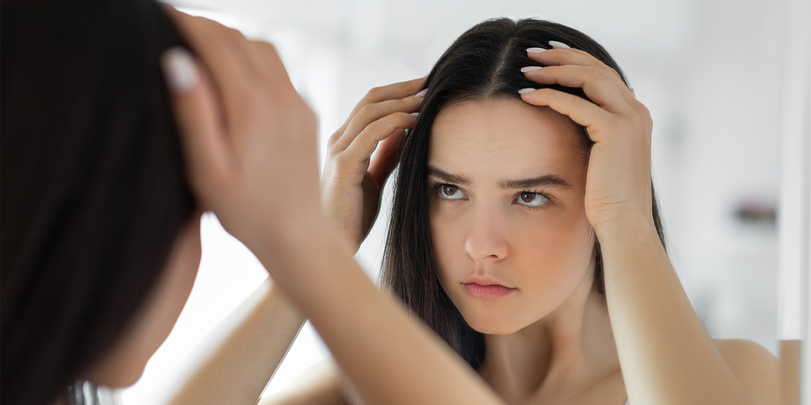 femme regardant ses cheveux dans le miroir