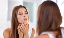 Une femme regarde ses boutons dans le miroir