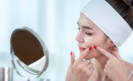 Une femme regarde ses boutons dans un miroir