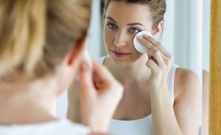 Une femme avec de l'acné se nettoie le visage