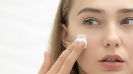 Une femme met de la crème pour peau grasse