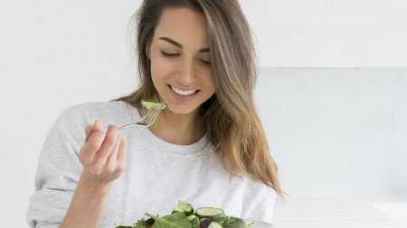 Une femme mange une salade de légumes