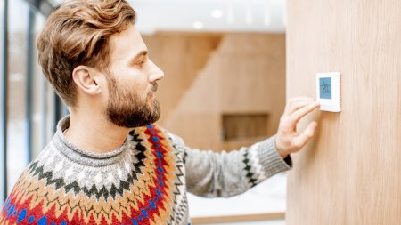 Un homme règle son thermostat