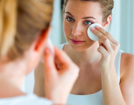 Femme qui se démaquille devant un miroir