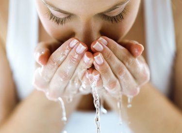Une femme nettoie son visage avec de l'eau