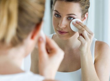 Une femme qui se nettoie le visage avec un coton