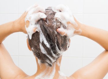 Une femme avec un psoriasis se nettoie les cheveux