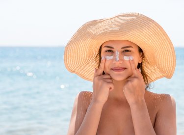 Une femme se met de la crème solaire