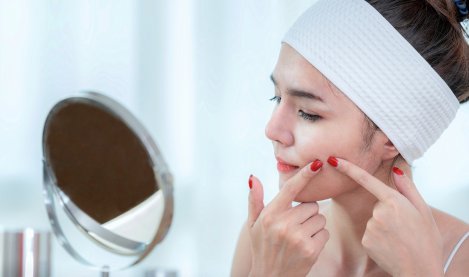 Une femme regarde ses boutons dans un miroir