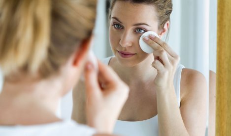 Une femme avec de l'acné se nettoie le visage