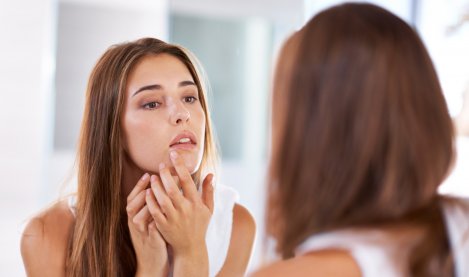 Une femme regarde ses boutons dans le miroir